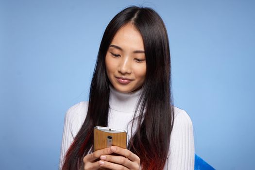 pretty brunette with phone in hand communication internet technology blue background. High quality photo