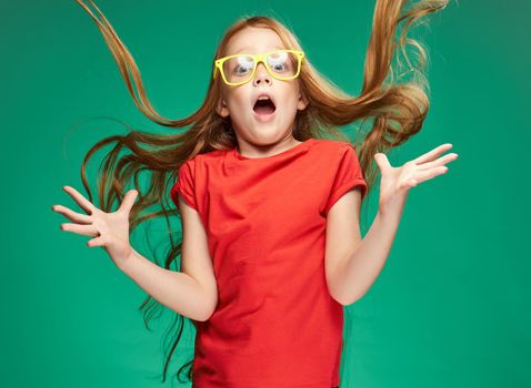 girl in a red T-shirt with loose hair emotions yellow glasses Green background. High quality photo