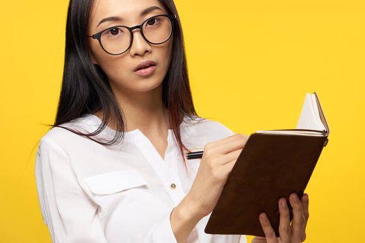 woman with a notebook in her hands in a white shirt official manager yellow background. High quality photo