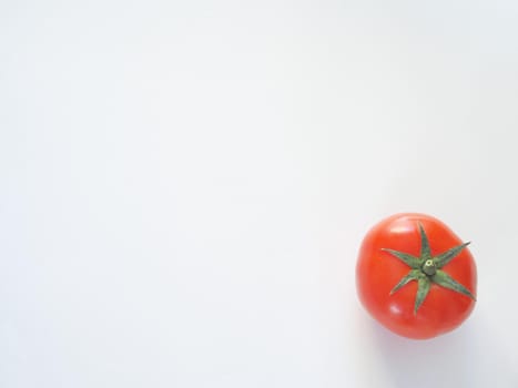 One red tomato on a white background is a close-up.