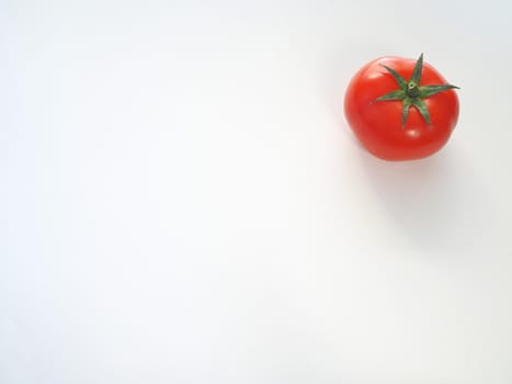 One red tomato on a white background is a close-up.