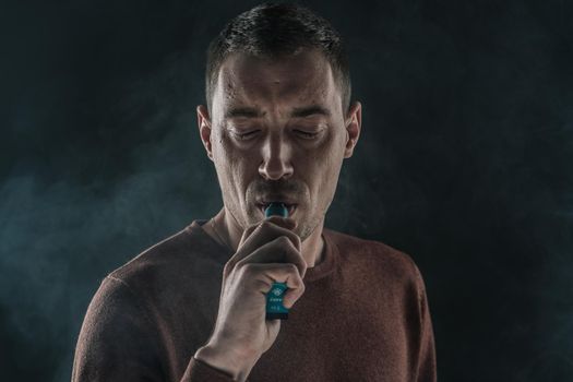 handsome man smoking vape on black background close-up. High quality photo