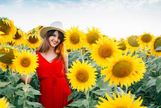 woman with red dress and hat in sunflowers field.