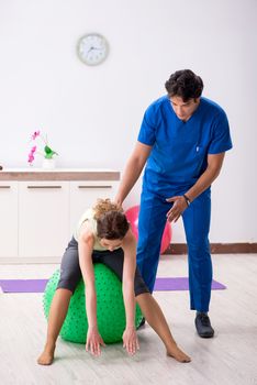 Fitness instructor helping sportsman during exercise