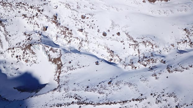 A huge wall of ice. Bogdanovich Glacier in the mountains of Almaty. The wind blows the snow away from the high frozen wave. Unusual shape and color of the ice. Moraine lake in winter in the mountains