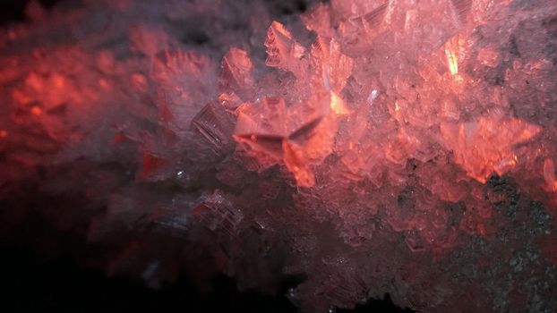 Macro photography of ice growths in a cave. Snow and ice of interesting shapes grow on the walls of the cave. Stalactites hang. Huge ice walls shimmer from the light of the lantern. Almaty, Kazakhstan