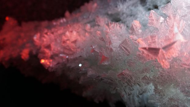 Macro photography of ice growths in a cave. Snow and ice of interesting shapes grow on the walls of the cave. Stalactites hang. Huge ice walls shimmer from the light of the lantern. Almaty, Kazakhstan