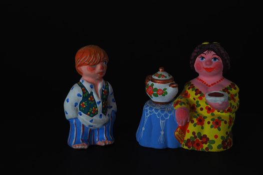 Ceramic figurines. A woman with a kettle, a samovar. Tea party. Close-up.