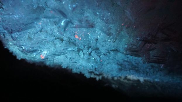 Macro photography of ice growths in a cave. Snow and ice of interesting shapes grow on the walls of the cave. Stalactites hang. Huge ice walls shimmer from the light of the lantern. Almaty, Kazakhstan