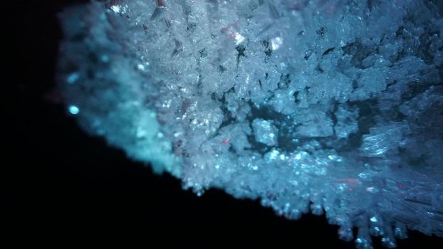 Macro photography of ice growths in a cave. Snow and ice of interesting shapes grow on the walls of the cave. Stalactites hang. Huge ice walls shimmer from the light of the lantern. Almaty, Kazakhstan