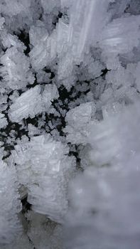 Macro photography of ice growths in a cave. Snow and ice of interesting shapes grow on the walls of the cave. Stalactites hang. Huge ice walls shimmer from the light of the lantern. Almaty, Kazakhstan