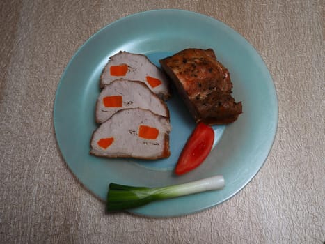 Slicing baked pork with vegetables on a beautiful plate.