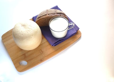 A large piece of cheese on a wooden tray with fresh bread. A high-quality photo. Close-up