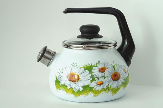 The kettle is an enamelled classic with a whistle. White with daisies. White background,