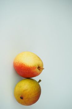 Two ripe pears on a white background. Vertical image. Close-up.