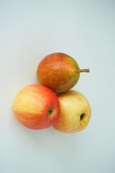 Ripe fruit, two apples and one pear on a white background, vertical image.