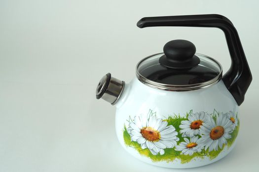 Kettle enamelled white with whistle, drawing of chamomile. High quality photo