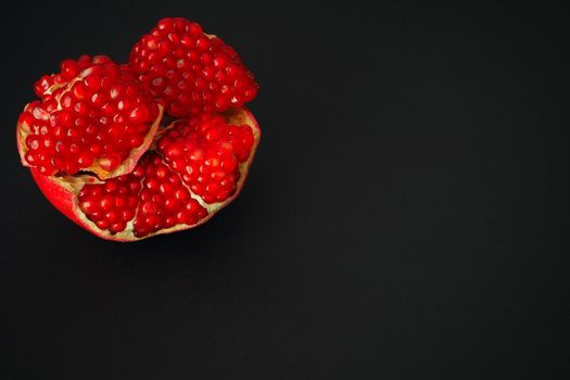 The fruit of a ripe pomegranate. Red fruit with juicy grains. Isolated on a black background. Close-up.