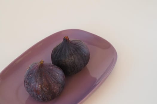 The figs are purple on an oval platter. High quality photo