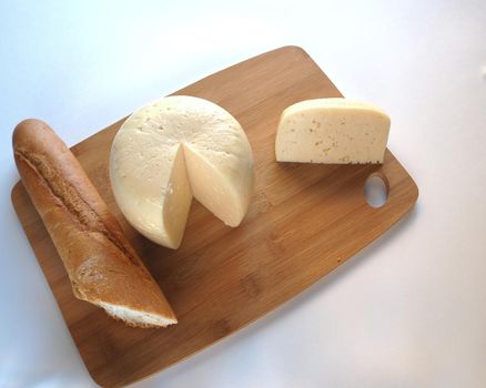 A large piece of cheese on a wooden tray with fresh bread. A high-quality photo. Close-up