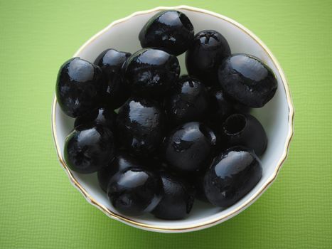 Black pitted olives in a salad bowl, close-up, high-quality photo.