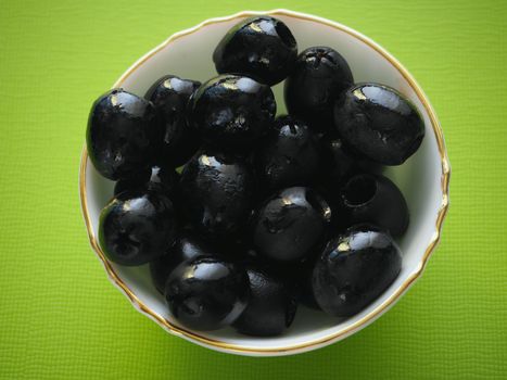 Black pitted olives in a salad bowl, close-up, high-quality photo.