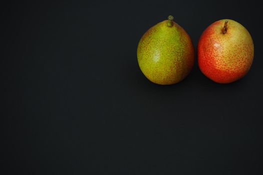 Ripe fruit. Two beautiful close-up pears, a black background.