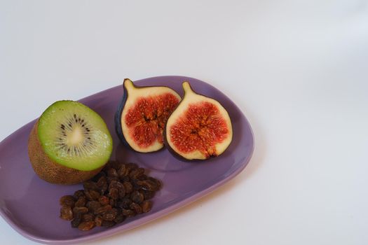 Exotic fruits and berries. Purple figs, kiwi and raisins on a platter. High quality photo