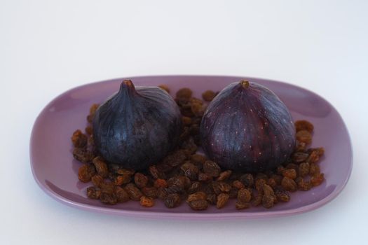 Fruit. Fig and raisins on a purple platter. White background. Close-up. High quality photo