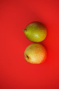 Ripe fruit on a red background. Beautiful pears and apples, Vertical image. Close-up.
