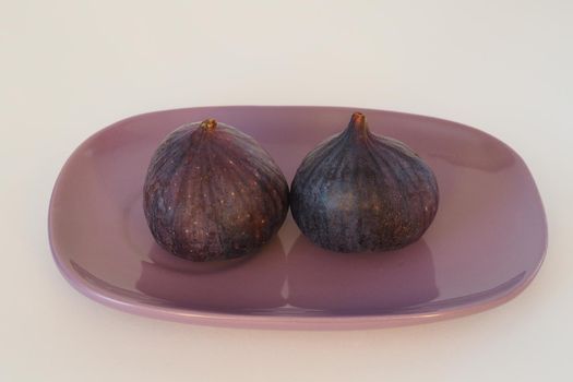The figs are purple on an oval platter. High quality photo