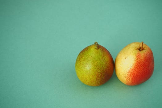 Two ripe pears close up on a green background. Horizontal image. Bright picture.