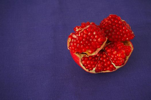 The fruit of a ripe pomegranate, red fruit with juicy grains. Isolated on a blue background.