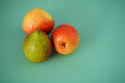 Ripe fruit. Beautiful pears and apples on a green background.