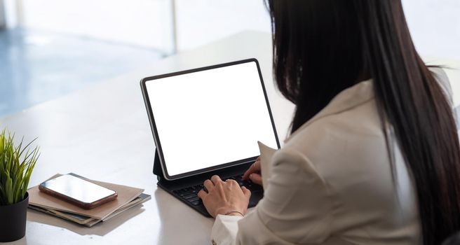 Cropped shot of business woman hand while typing on computer tablet with blank screen and sitting next to her colleague.
