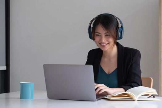 Happy asian woman wear headset laugh using laptop video stream conference call teach online, happy ethnic girl student gamer tutor have fun watch webinar web cam education entertainment concept.