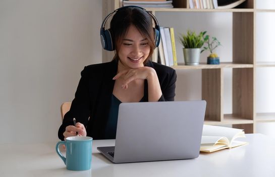 Happy asian woman wear headset laugh using laptop video stream conference call teach online, happy ethnic girl student gamer tutor have fun watch webinar web cam education entertainment concept.