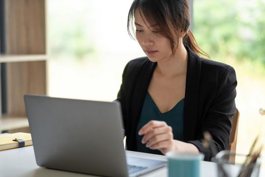 Asian businesswoman use a computer laptop and thinking idea for her business,