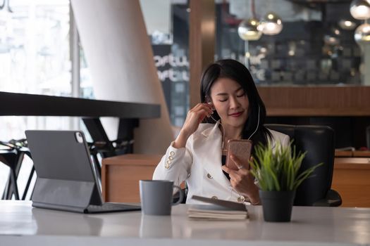 Relax Time - Businesswoman with headphones sitting at the desk indoors in office.