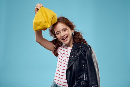 Fashionable girl in a black jacket with a yellow ticket striped T-shirt blue background. High quality photo