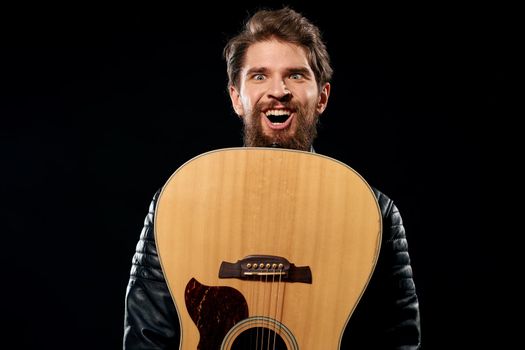 A man with a guitar in his hands leather jacket music performance rock star modern style dark background. High quality photo
