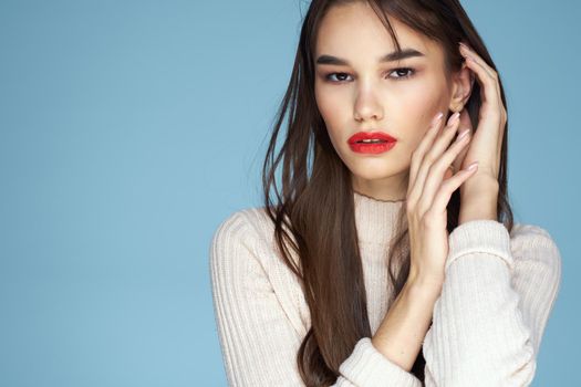 Brunette in a white sweater red lips charm long hair blue background. High quality photo