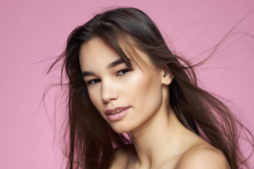 Pretty brunette naked shoulders clear skin pink background. High quality photo
