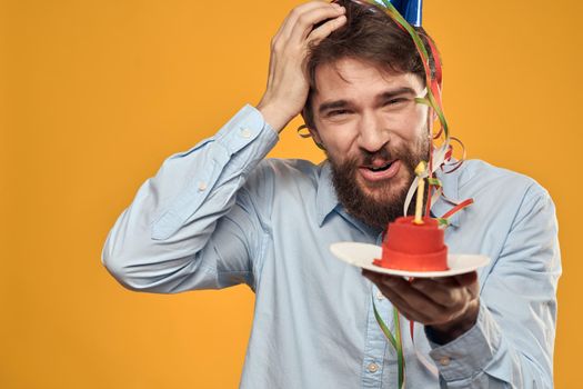 Birthday boy in a cap with a birthday cake in his hand and a candle. High quality photo
