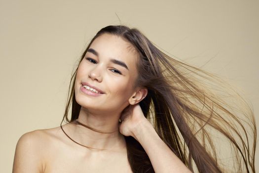 Pretty woman naked shoulders cosmetics clean skin hair care beige background. High quality photo