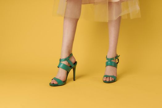 Female legs green shoes elegant lifestyle yellow background. High quality photo