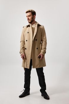 gentlemen in a beige coat and full-length trousers on a light background hairstyle model glasses. High quality photo