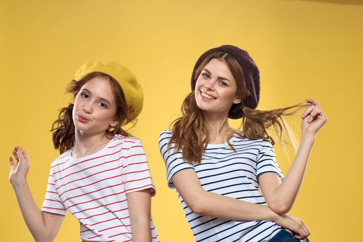funny mom and daughter wearing hats fashion fun joy family yellow background. High quality photo