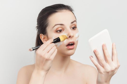 pretty woman applying brush cream on face skin care rejuvenation. High quality photo