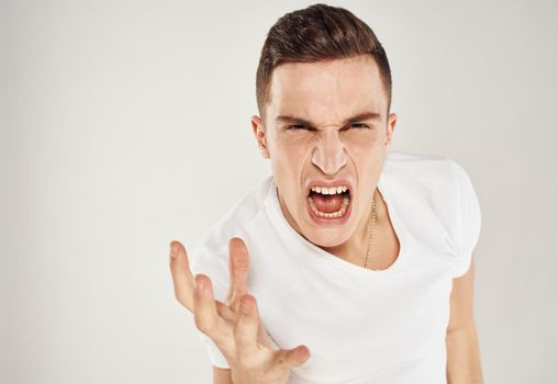 Emotional man in a white T-shirt gestures with his hands on a light background model stress irritability. High quality photo